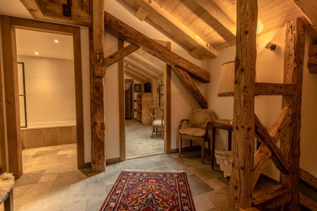 Corridor avec charpente apparente, mobilier vintage, vue traversante, tapis persan, peau de mouton