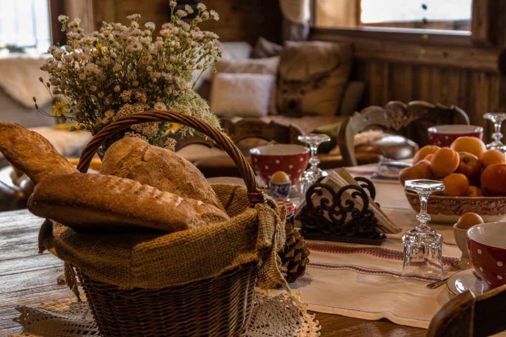 Zoom sur table dressée pour le petit déjeuner : pain frais, œufs à la coque, fruits de saison, fleurs de montagne fraichement cueillies