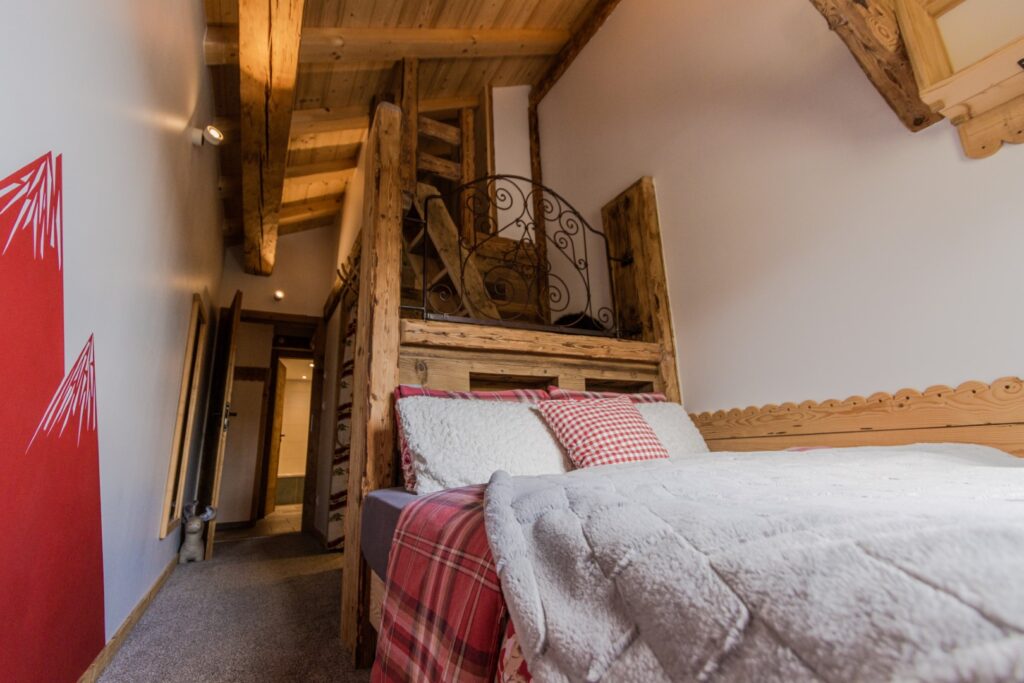 Chambre double en suite : tête de lit bois et fer forgé, escalier meunier vers mezzanine lit d'appoint