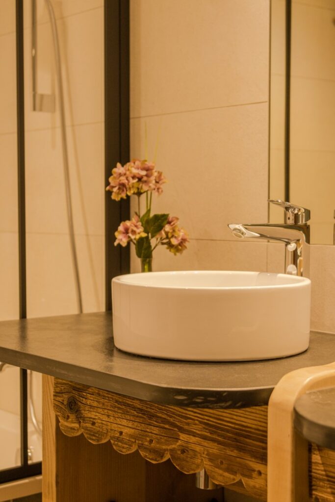 Salle d'eau stylée : vasque blanche, robinetterie de qualité, déco fleurie